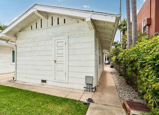 A white wooden house with a green door and windows.