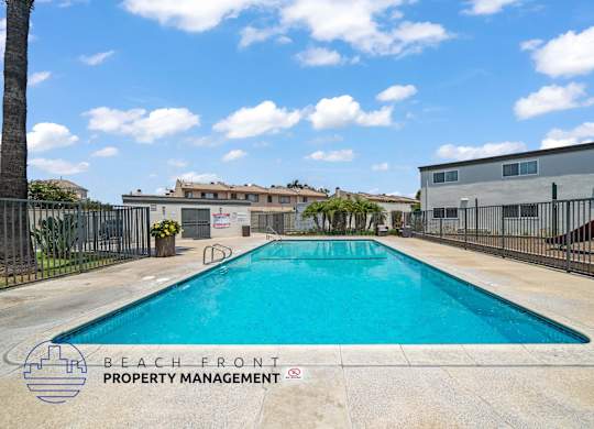A pool surrounded by a fence with the words Beach Front Property Management.