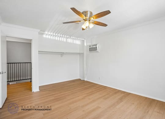 A room with a ceiling fan and wooden flooring.
