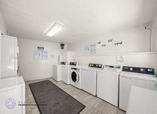 A laundry room with washers and dryers and a sign that says Beach Front Property Management.