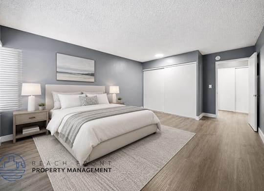 A well-lit bedroom with a large bed and a nightstand with a lamp.
