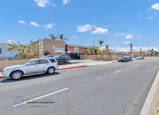 A street view with a car driving on the road and a building on the side.