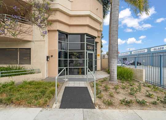 A building with the number 730 on it has a glass door and a ramp leading up to it.