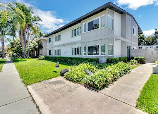 A modern two-story house with a white exterior and a landscaped front yard.