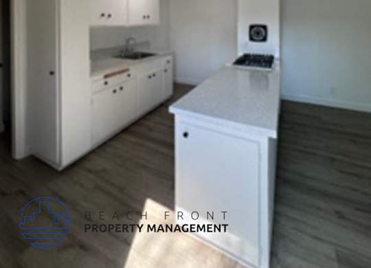 A white kitchen with a skylight and a logo for Beach Front Property Management.