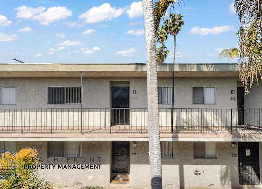 A building with a balcony and a palm tree in front of it.