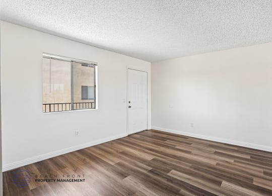 A room with a wooden floor and a window with bars on it.