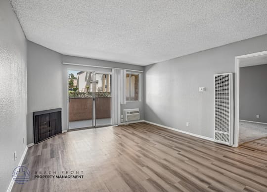 A spacious room with wooden flooring and a fireplace.