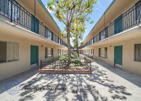 A courtyard with a tree and a fence in the middle of a building complex.