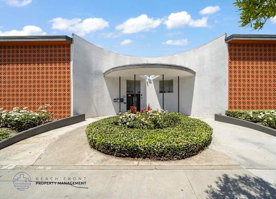 A modern building entrance with a circular flower bed in front.
