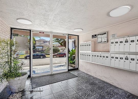 A view of a parking garage with a glass door and a wall of mailboxes.