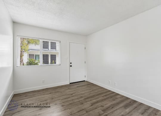 A room with a white door and a window with blinds.