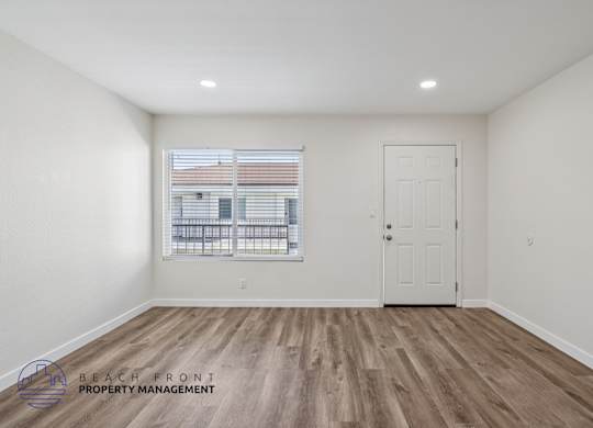 A room with a wooden floor and a window with blinds.