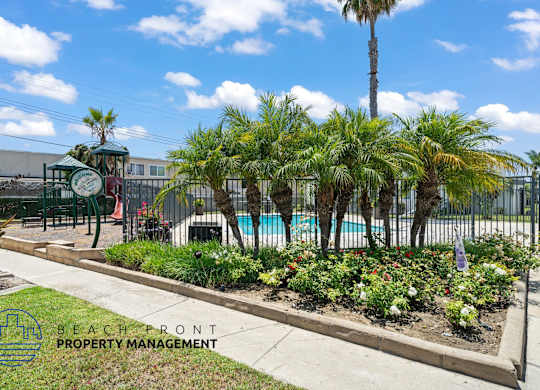 A pool area with a fence and a sign that says Beachfront Property Management.