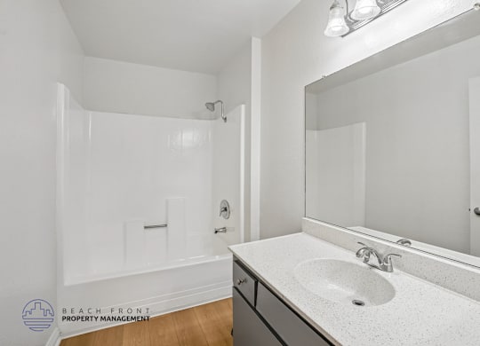 A bathroom with a sink, mirror, and shower.