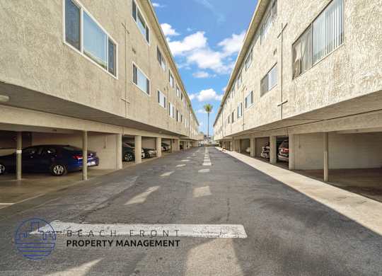A long, empty parking garage with a logo for Beach Front Property Management in the bottom left corner.