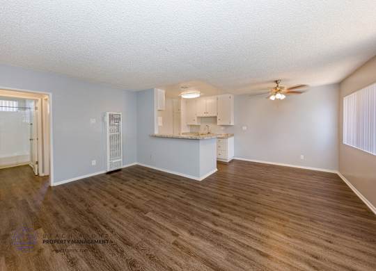 A spacious room with wooden flooring and a ceiling fan.