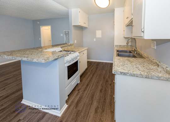 A kitchen with a granite countertop and white cabinets.
