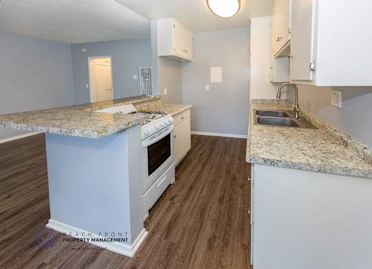 A kitchen with a granite countertop and white cabinets.