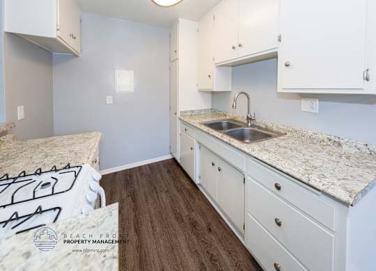 A kitchen with white cabinets and a granite countertop.