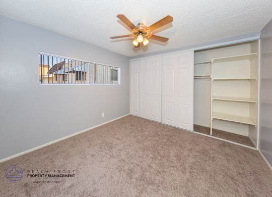 A room with a fan and a window overlooking a balcony.