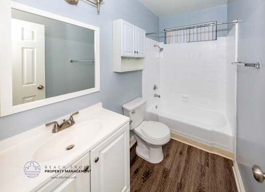 A white bathroom with a toilet, sink, and shower.