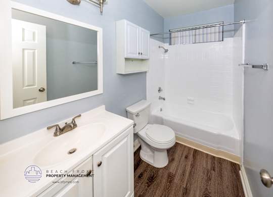 A white bathroom with a toilet, sink, and shower.