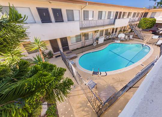 A swimming pool is surrounded by a fence and chairs.