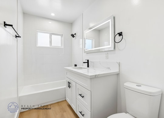 A white bathroom with a toilet, sink, and mirror.