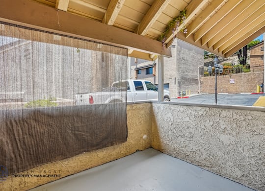 A covered outdoor area with a wooden ceiling and a concrete wall.
