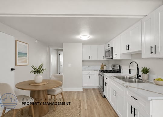 A kitchen with white cabinets and a round table with chairs.