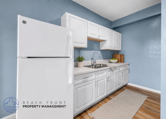 A kitchen with white cabinets and a white refrigerator.