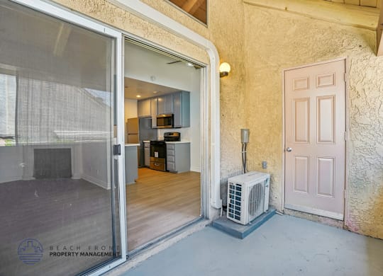 A room with a sliding glass door leading to a kitchen area.