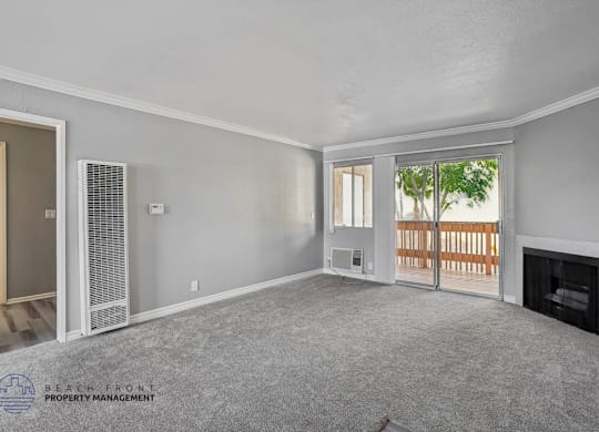 A spacious living room with a fireplace and sliding glass doors leading to a balcony.