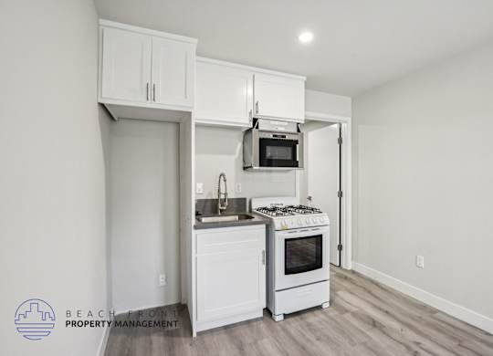 A kitchen with white cabinets and a stove top oven.