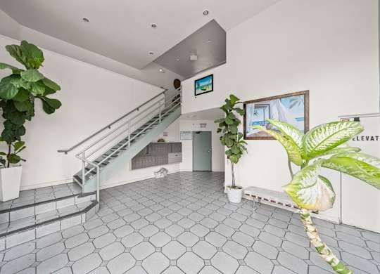 A white room with a grey tiled floor and a staircase.