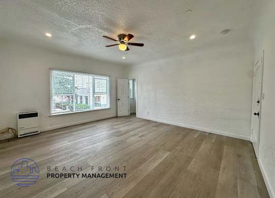 A spacious room with wooden flooring and a ceiling fan.