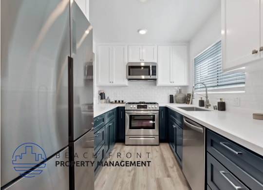 a kitchen with blue and white cabinets and stainless steel appliances