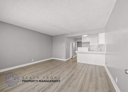 A room with wooden flooring and a logo for Beach Front Property Management.