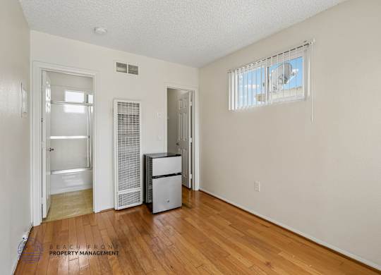 A room with a wooden floor and a window with blinds.