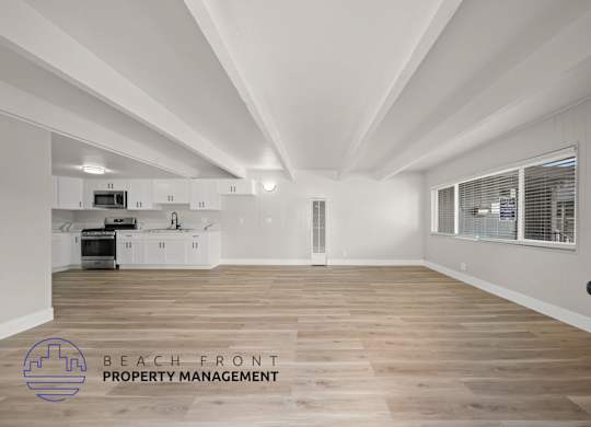 A spacious kitchen with wooden floors and white walls.