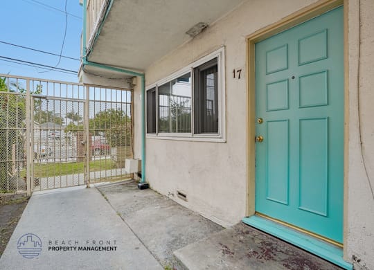A blue door is on the front of a house with a sign that says Beach Front Property Management.