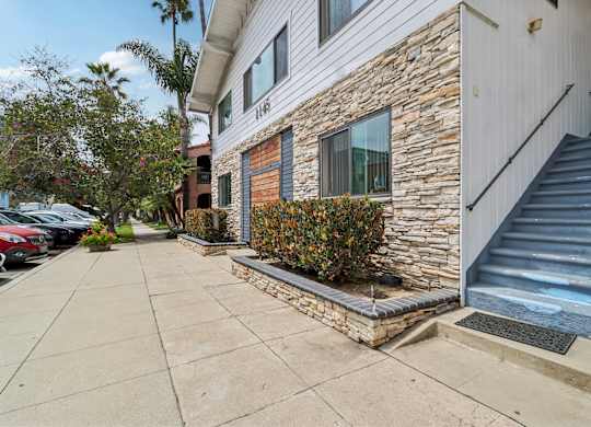 A house with a stone wall and a staircase leading to the entrance.