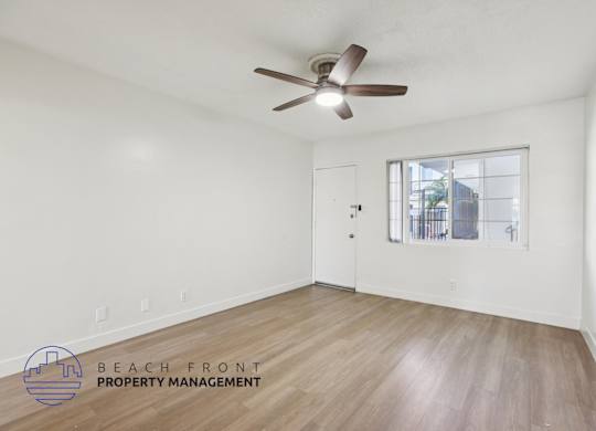 A room with a ceiling fan and wooden flooring.