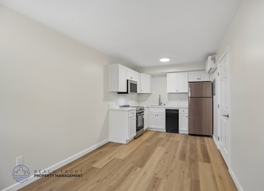 A kitchen with white cabinets and a wooden floor.
