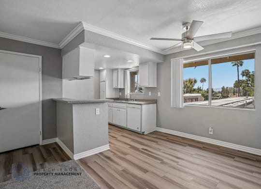 A well-lit kitchen with a ceiling fan and a view of the outdoors through a window.