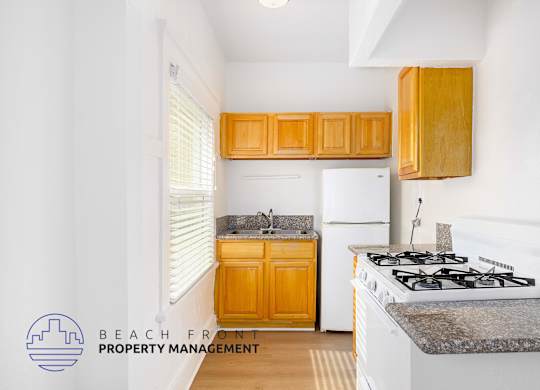 A kitchen with a stove, sink, and cabinets.