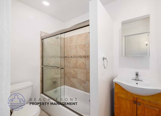 A bathroom with a glass shower door and a white sink.