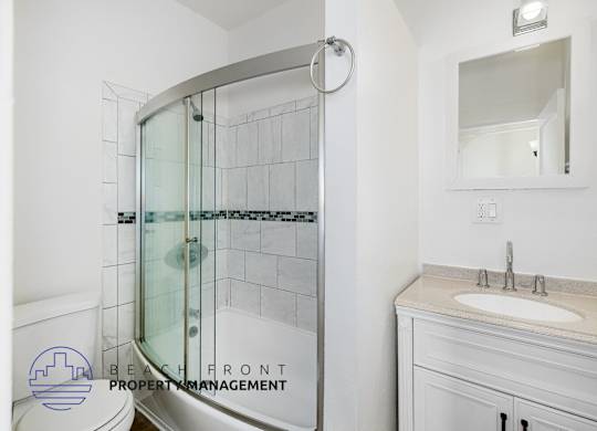 A bathroom with a white sink and a glass shower door.