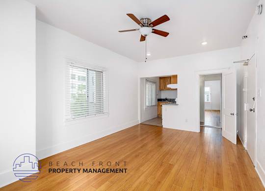 A spacious room with wooden floors and a ceiling fan.